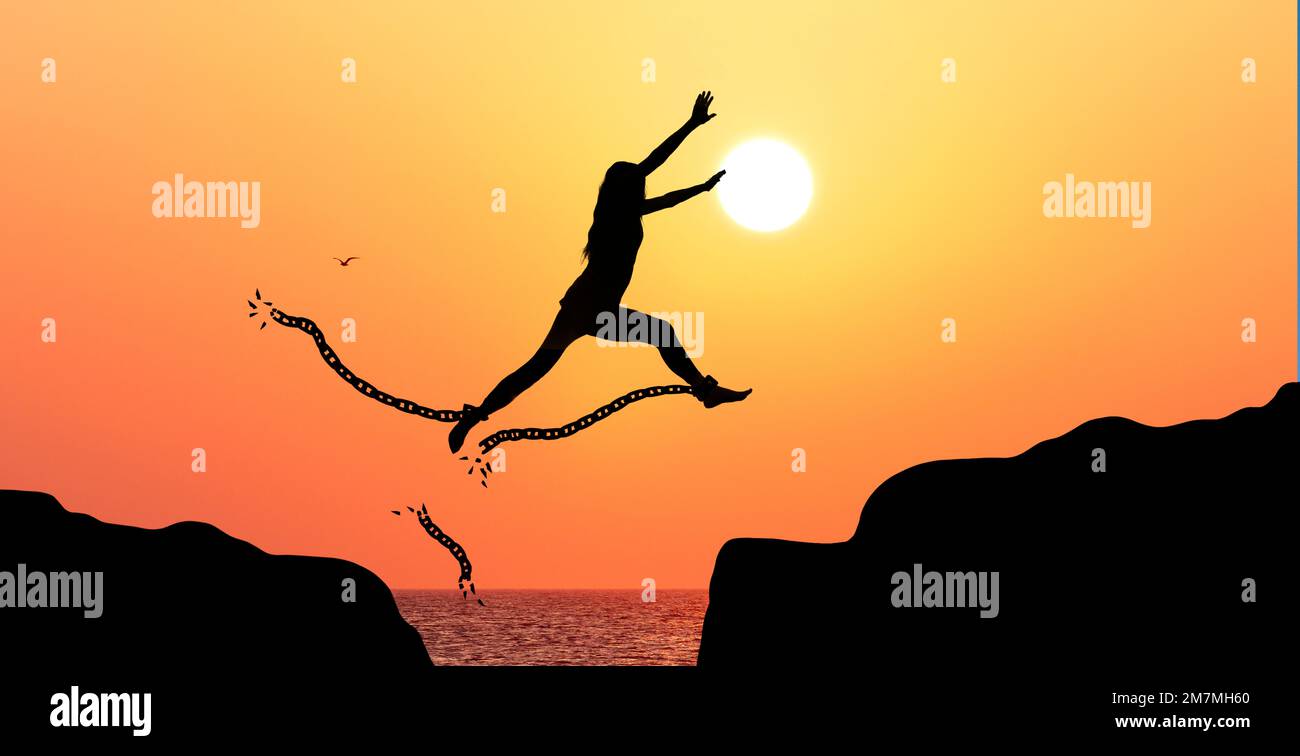 Silhouette of a woman jumping and bursting shackles Stock Photo