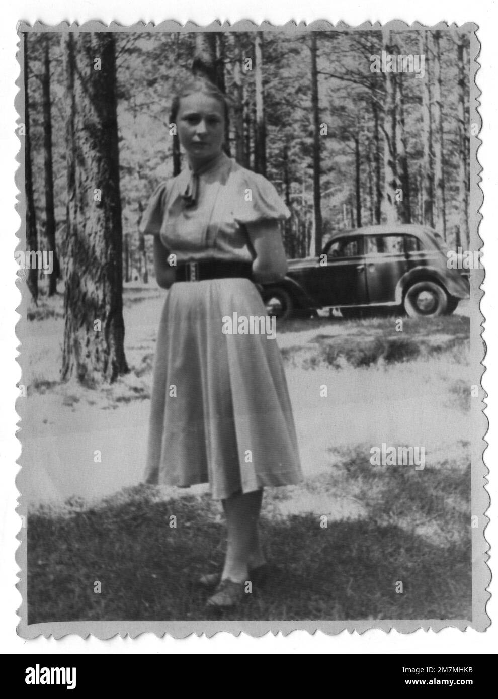 A young girl in the forest against the backdrop of a Moskvich car. Photo taken in 1955. Stock Photo