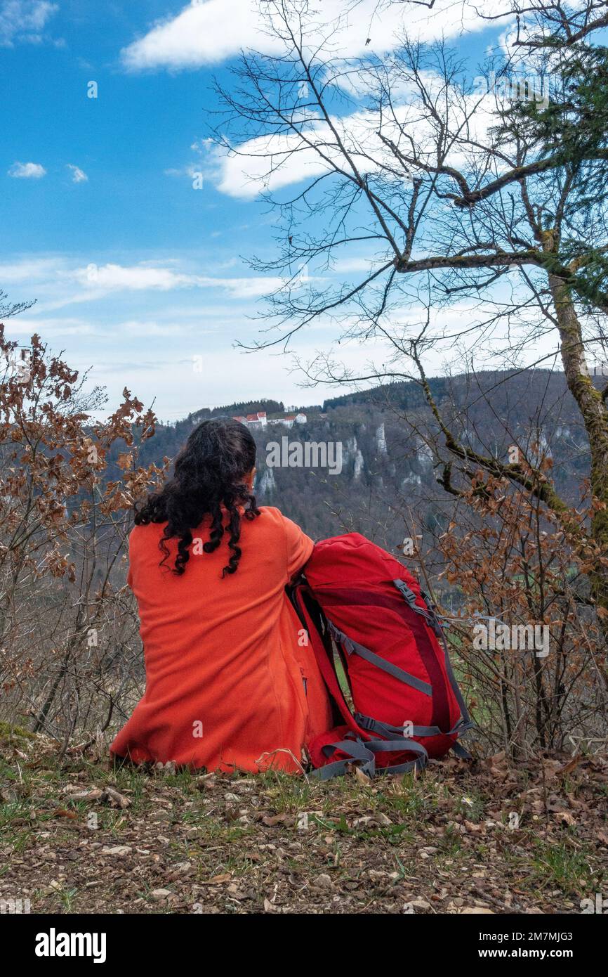 Europe, Germany, Southern Germany, Baden-Württemberg, Danube valley, Sigmaringen, Beuron, hiker sits on the ground and enjoys the view of Wildenstein Castle Stock Photo