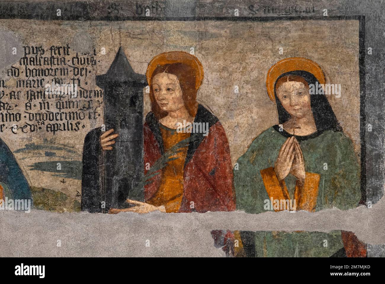 Female saints Barbara (left) and Margherita or Margaret of Cortona depicted in damaged Renaissance fresco, painted in 1512, on west front of deconsecrated Cappella di San Grato (Chapel of St Gratus) in Via Jean-Baptiste De Tillier in the historic centre of Aosta, regional capital of the Valle d’Aosta in northwest Italy.  Saint Barbara holds a three-windowed tower.  The tower symbolises Barbara’s imprisonment by her father.  The three windows - which she ordered be inserted in her prison - symbolise the Holy Trinity. Stock Photo