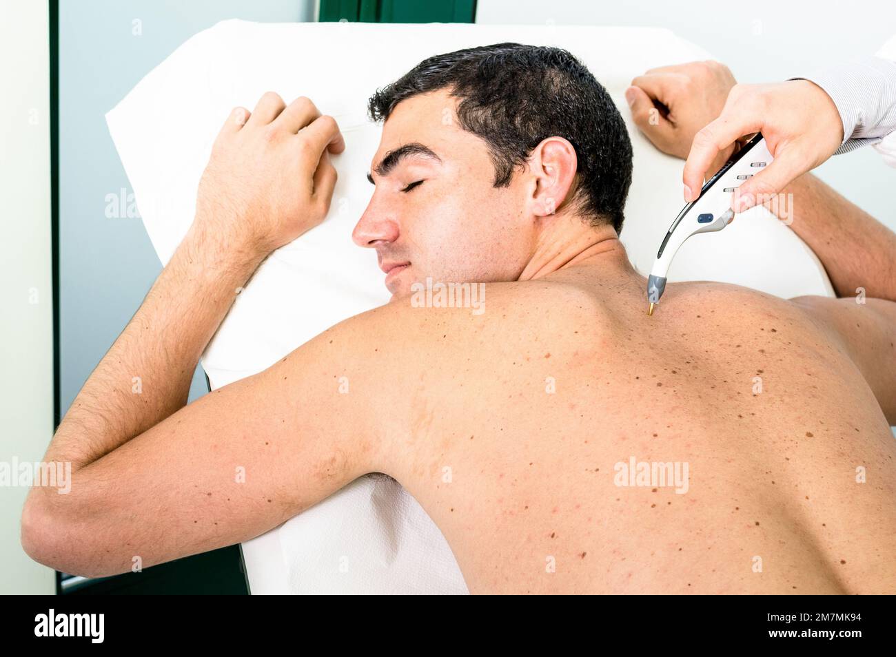 Young hipster primary doctor at work checking male patient in private clinic  - Concept of modern alternative medicine analyzing skin nevus diseases i Stock Photo