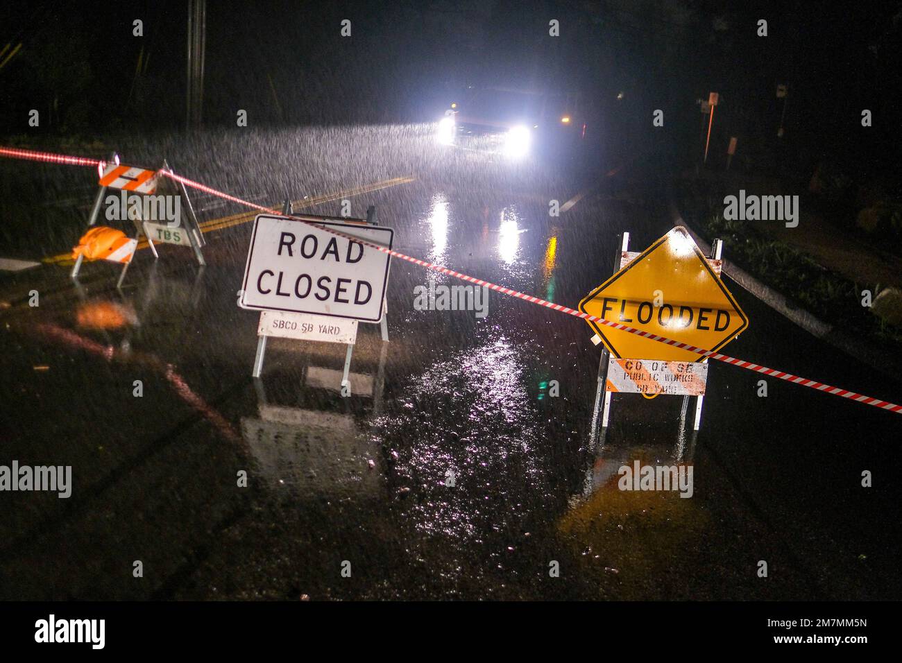 A flooded warning sign and a road closed to thru traffic sign are seen ...