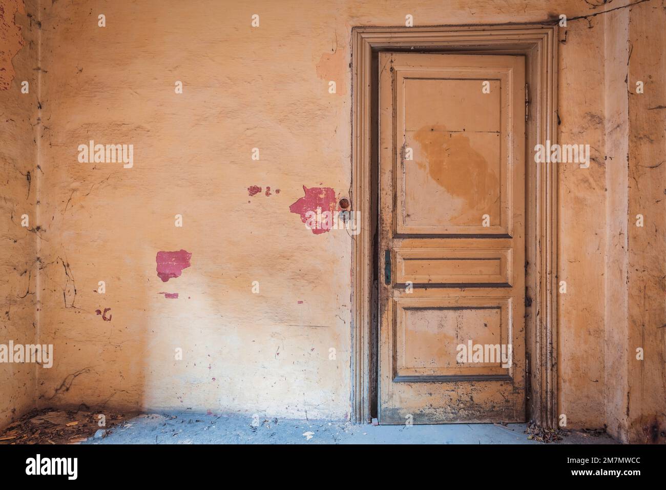 Italy, Veneto, dusty room of an abandoned house, closed door and salmon pink walls Stock Photo