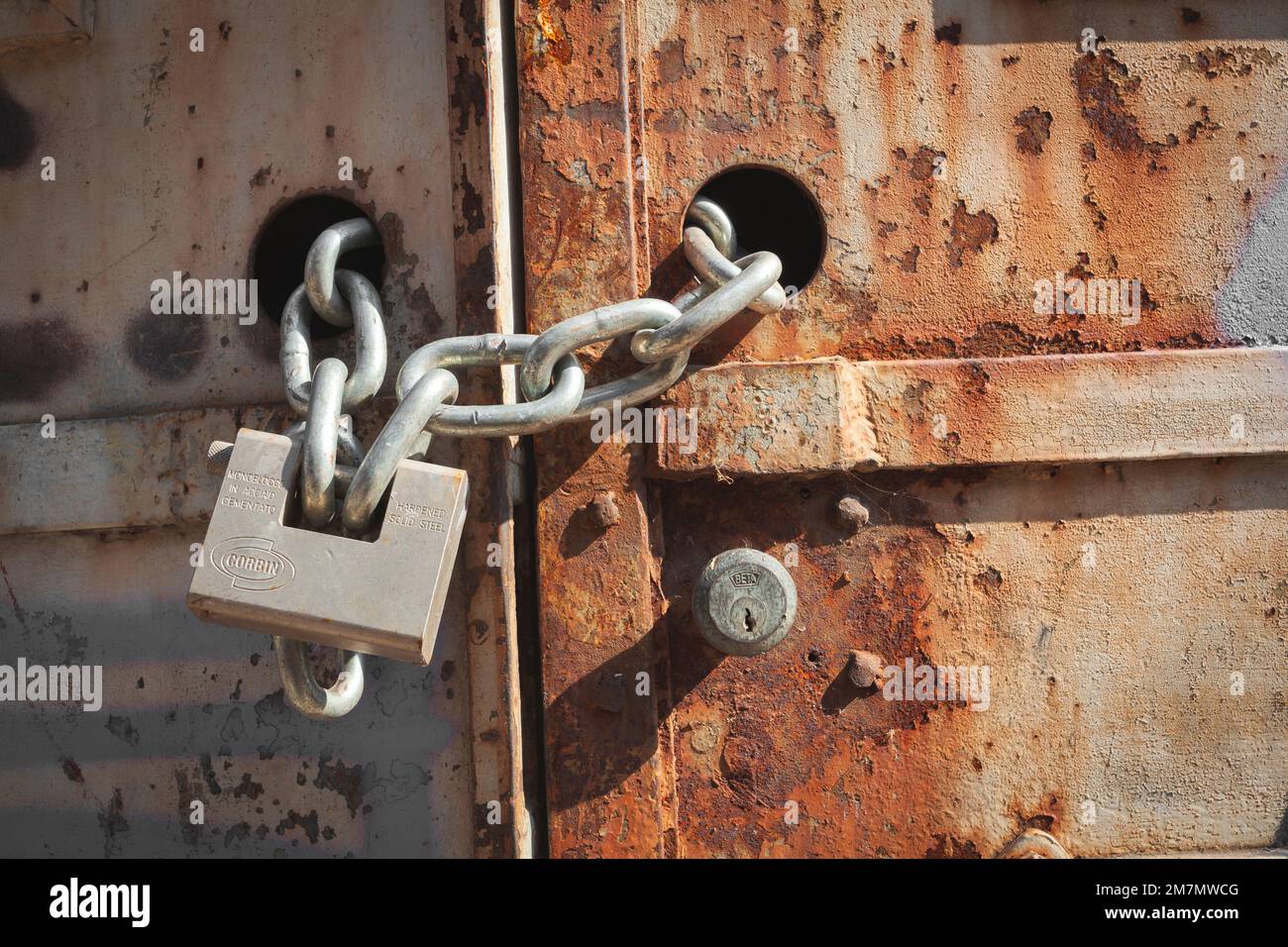 Italy, Veneto, rusty iron door closed by chain and padlock Stock Photo