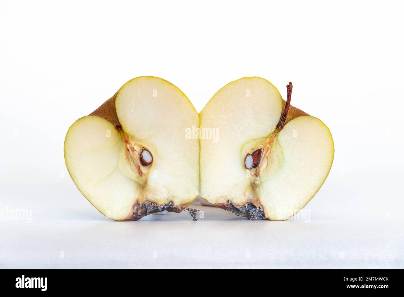 Spoiled, dehydrated and rotten apple, one apple cut in half, two apple halves, isolated on white background Stock Photo
