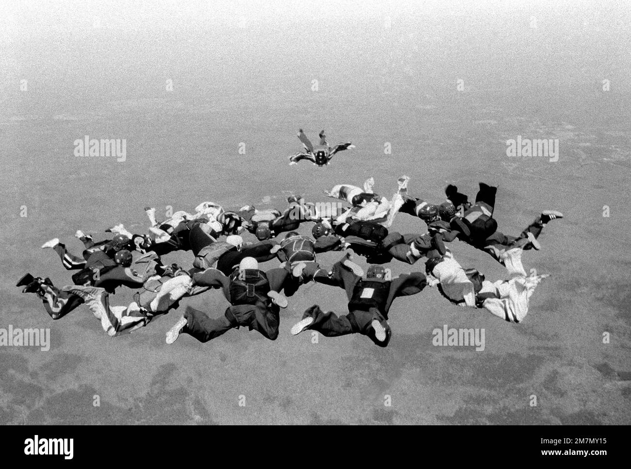 Fifteen Marines are holding hands at 9000 feet as another Marine prepares to join them. The group was completed with a record setting number of 18 Marines skydiving in a formation called snowflake at 5000 feet. They had jumped from a CH-53 Sea Stallion helicopter. The Skydiving club was formed in March 1975 at Quantico. Base: Marine Corps Base, Quantico State: Virginia (VA) Country: United States Of America (USA) Stock Photo