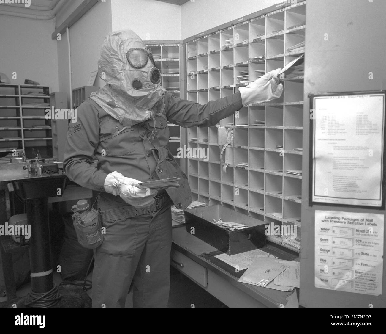 AIRMAN First Class Harry Leonard, postal clerk, sorts mail while wearing nuclear-biological-chemical gear during a test to evaluate his unit's ability to perform under fallout conditions. Base: Raf Mildenhall Country: Great Britain / England (GBR) Stock Photo