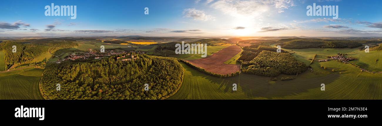 Germany, Thuringia, Meiningen, Henneberg, Einödhausen (right), Henneburg castle ruin, villages, mountains, fields, forest, sunrise, partly backlight, aerial view, 36ö° - panorama Stock Photo