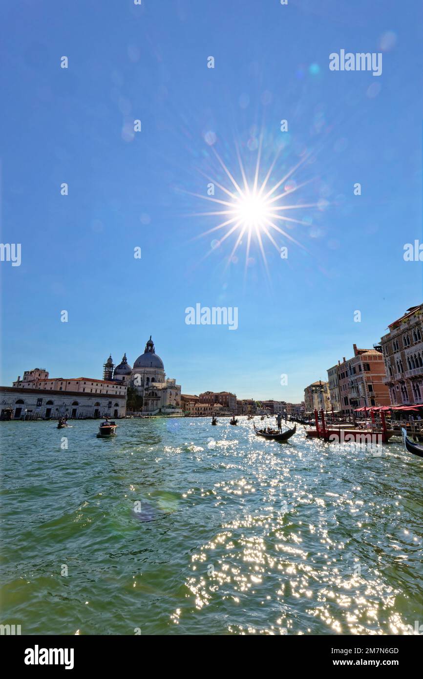 Gondolas drive tourists on the Grand Canal in Venice past houses, backlight shot Stock Photo