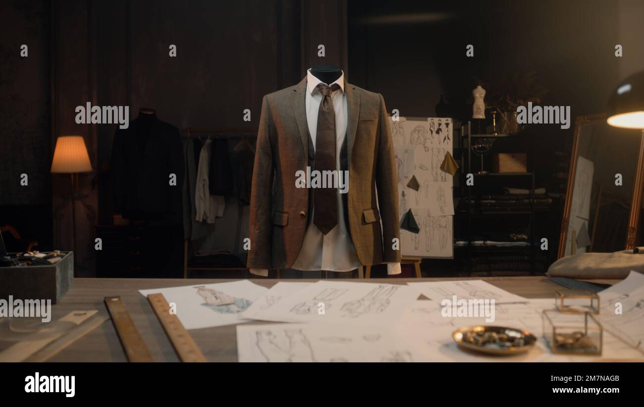 Mannequin with tailored shirt, tie and jacket in luxury designer atelier or tailoring studio. Table with tools, drawings and sketches of future clothes. Fashion, hand craft and couturier concept. Stock Photo
