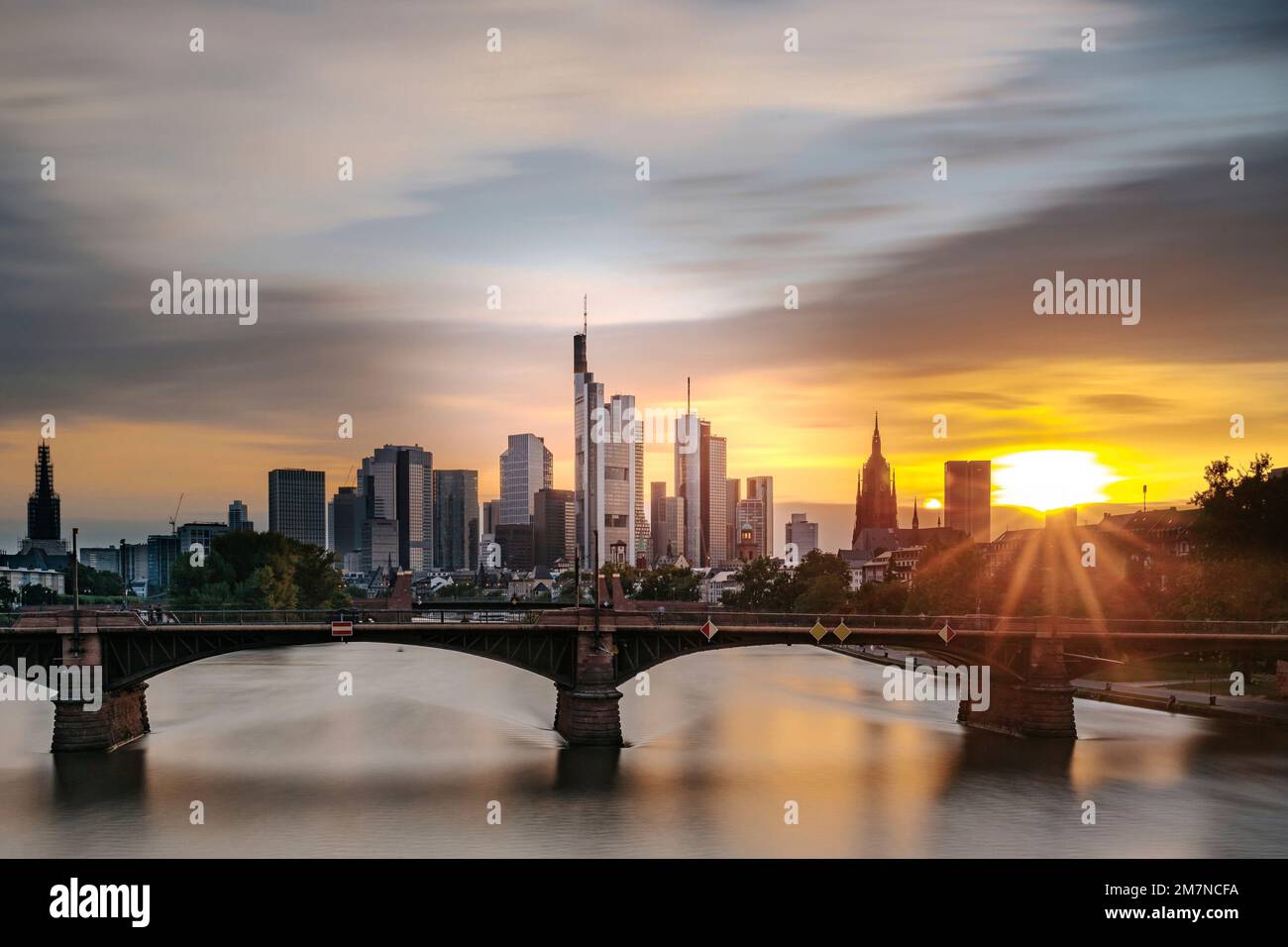 Long exposure with view over the Main River, the Ignatz Bubis Bridge and the skyline in the sunset. Backlight shot of Frankfurt am Main, Hesse, Germany Stock Photo