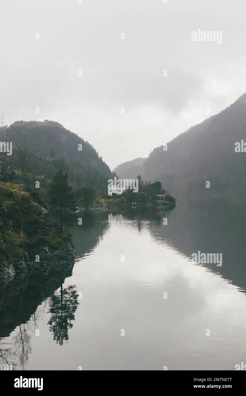 Lonely house on an island in Norway, landscape with reflection in the water, typical fjord landscape with small islands, isolation from the outside world, central perspective Stock Photo