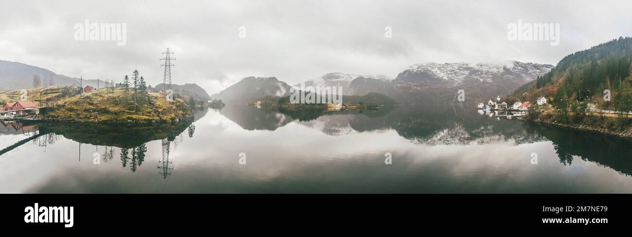 Panoramic image of fjord with group of islands, fishermen huts, houses, boats, power poles in Norway, landscape with lonely fishing village, typical f Stock Photo