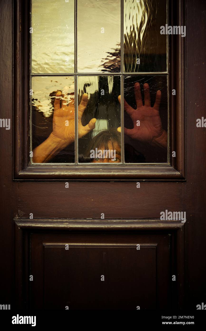 Man hiding behind old wooden door with raised hands Stock Photo