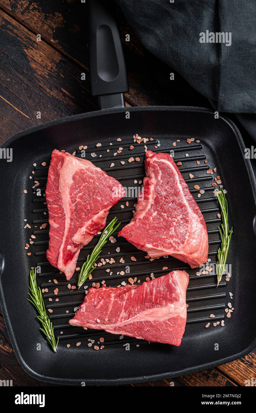 Raw sirloin beef steak, Rump steak cut on a grill skillet. Wooden ...
