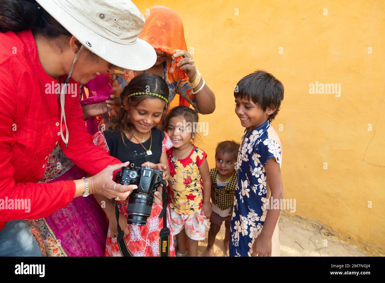 Jaisalmer, Rajasthan, India - 15th October 2019 : Female traveller and woman photographer showing pictures of smiling and happy Rajasthani children. Stock Photo
