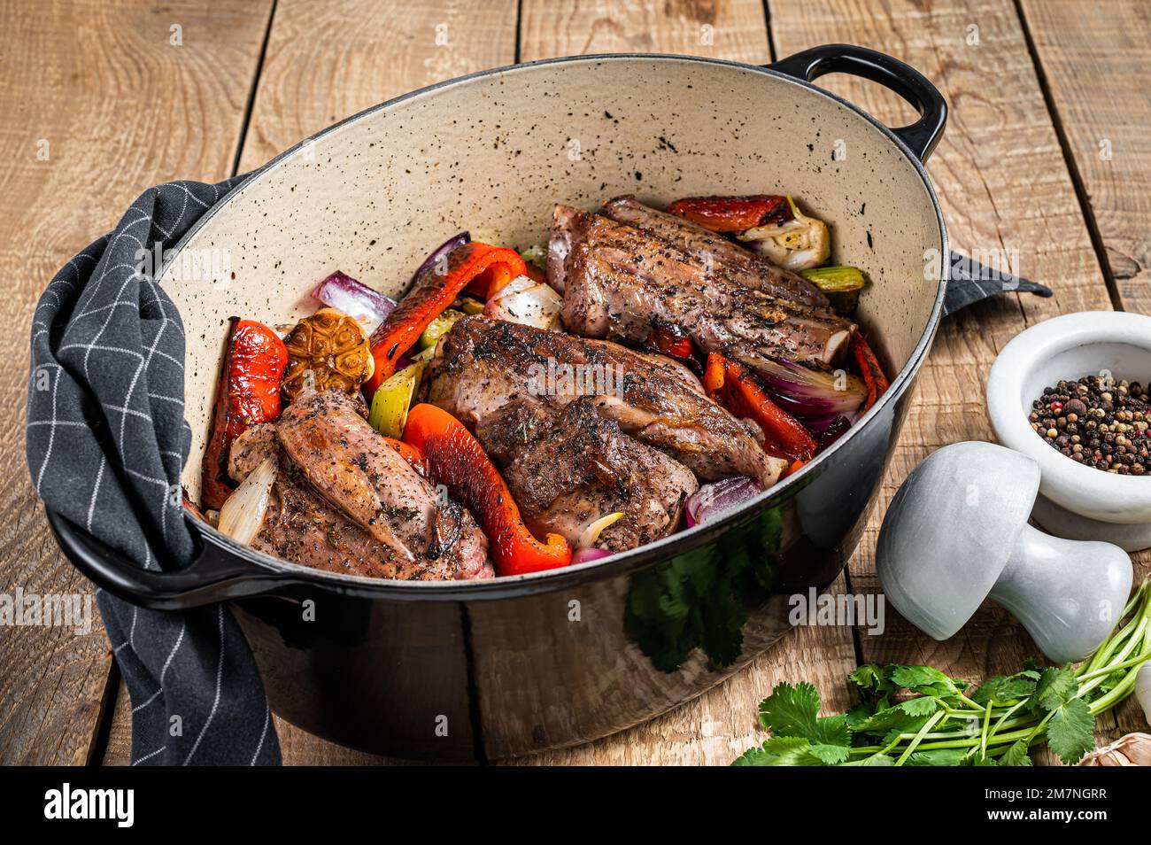 Roasted slow cooked lamb shanks with vegetables and herbs. Wooden