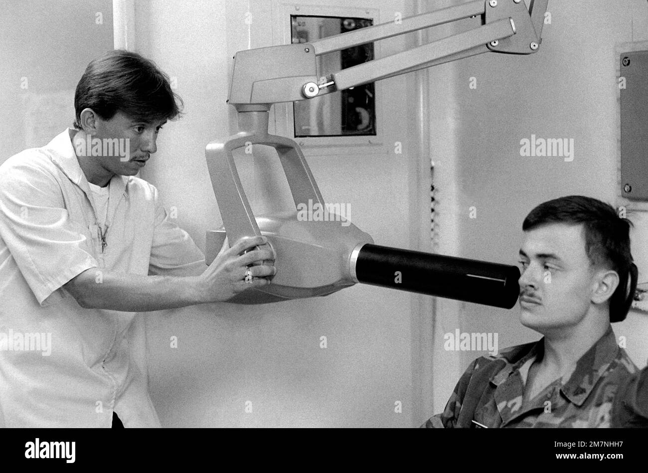 A Navy dental technician uses a general Xray machine to take Xrays of