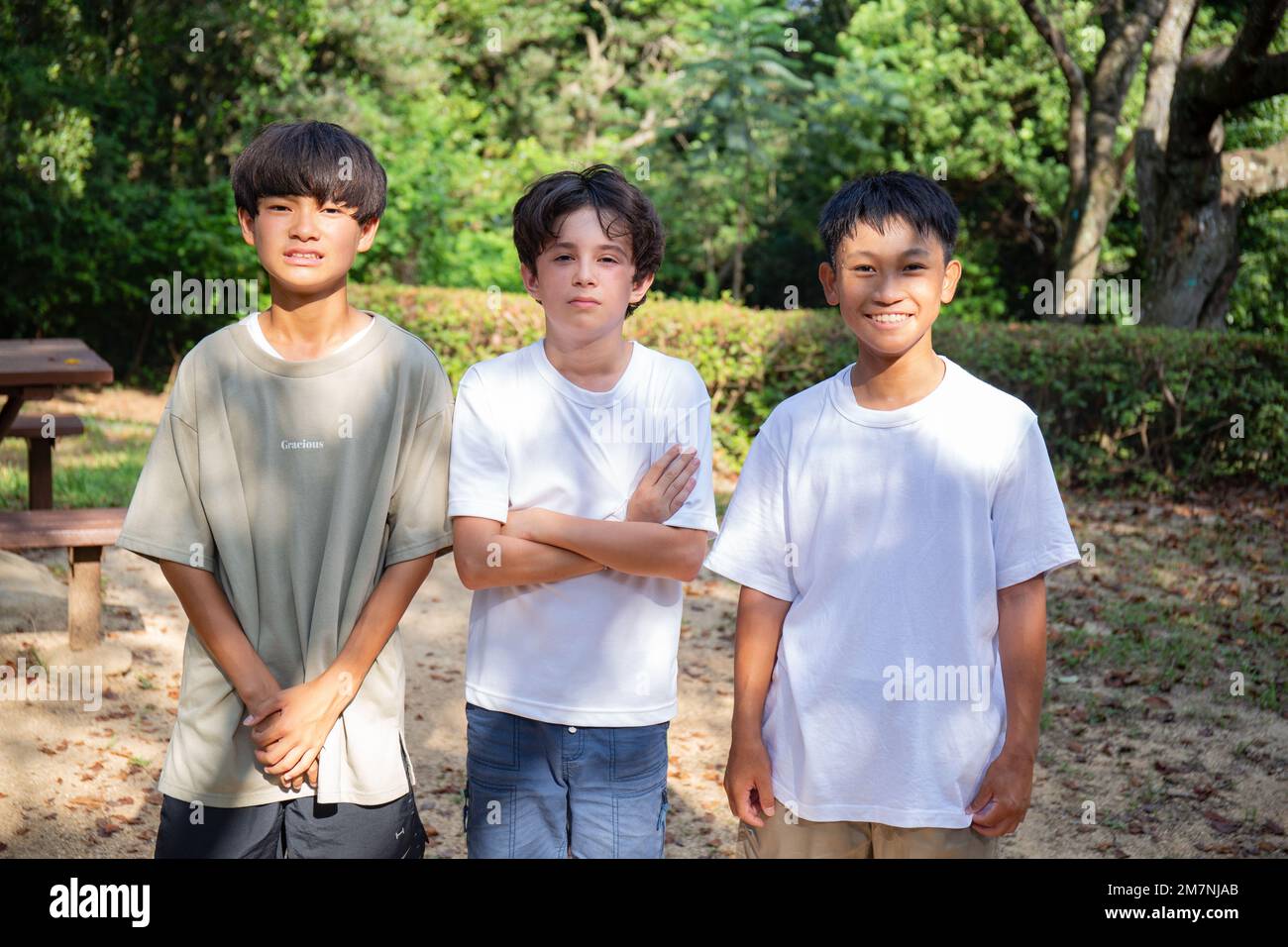 Three boys in a row, outdoors in the part in summer. Stock Photo