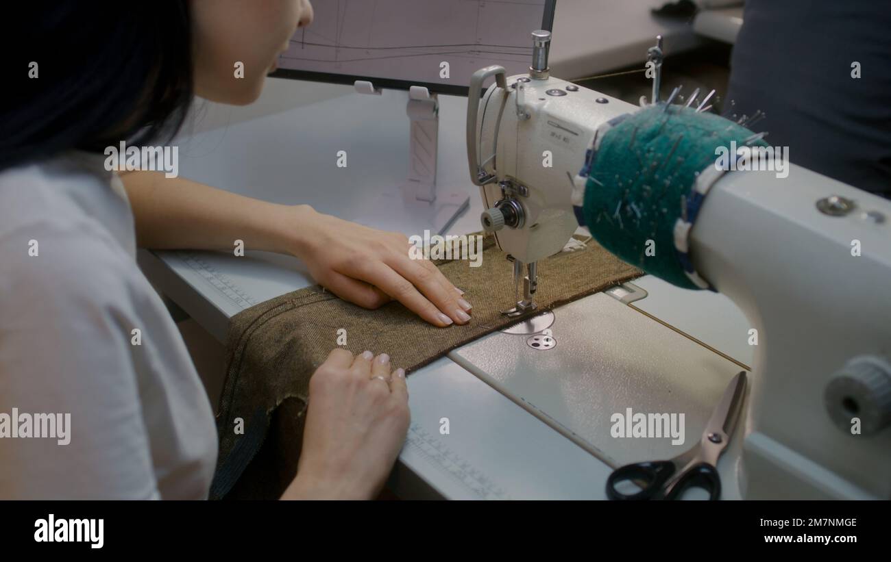 Sewing Machine Tablet Female seamstress or dressmaker sits at sewing machine and works with ...