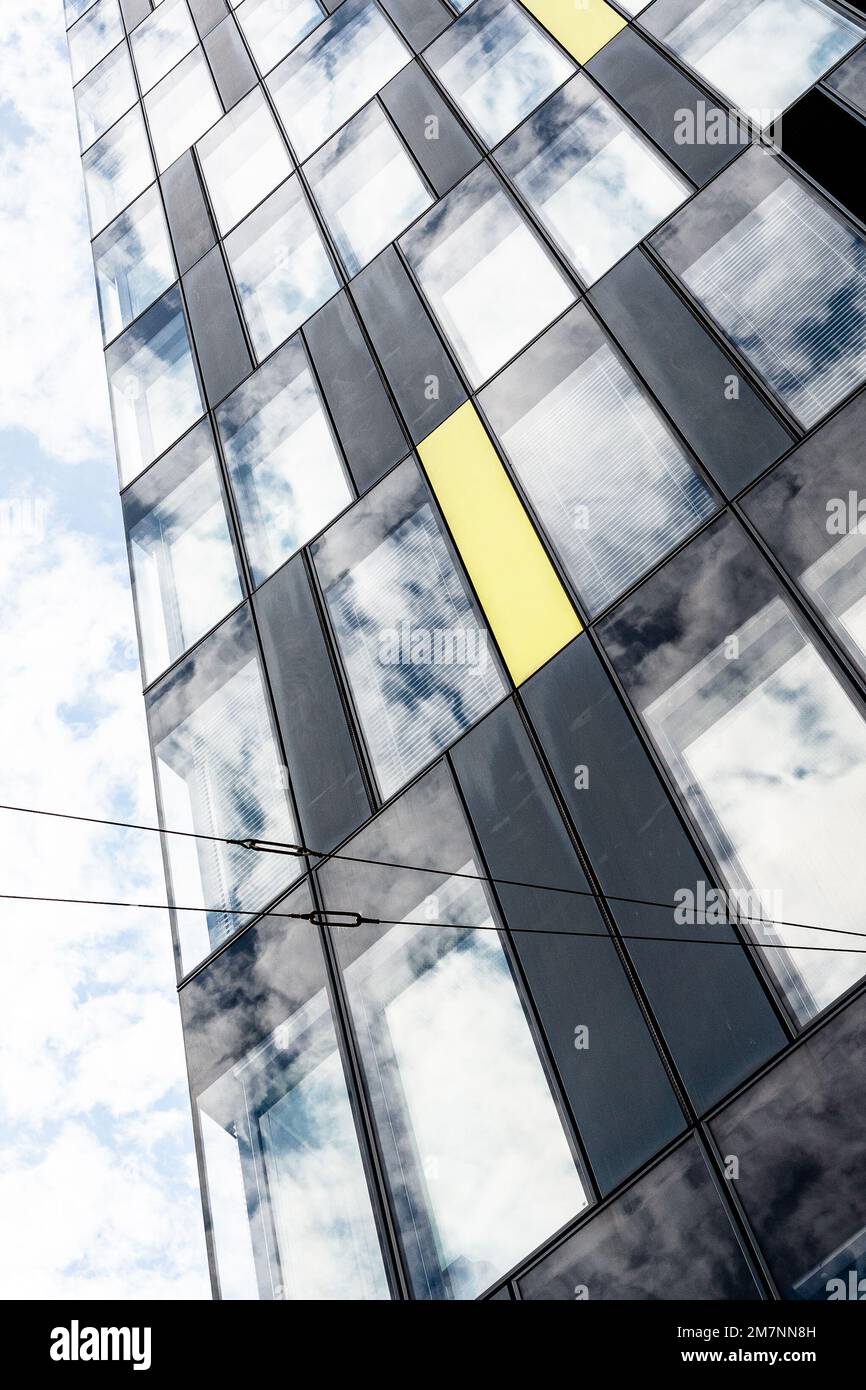 Blue sky and white clouds are reflected in the windows of a high-rise ...