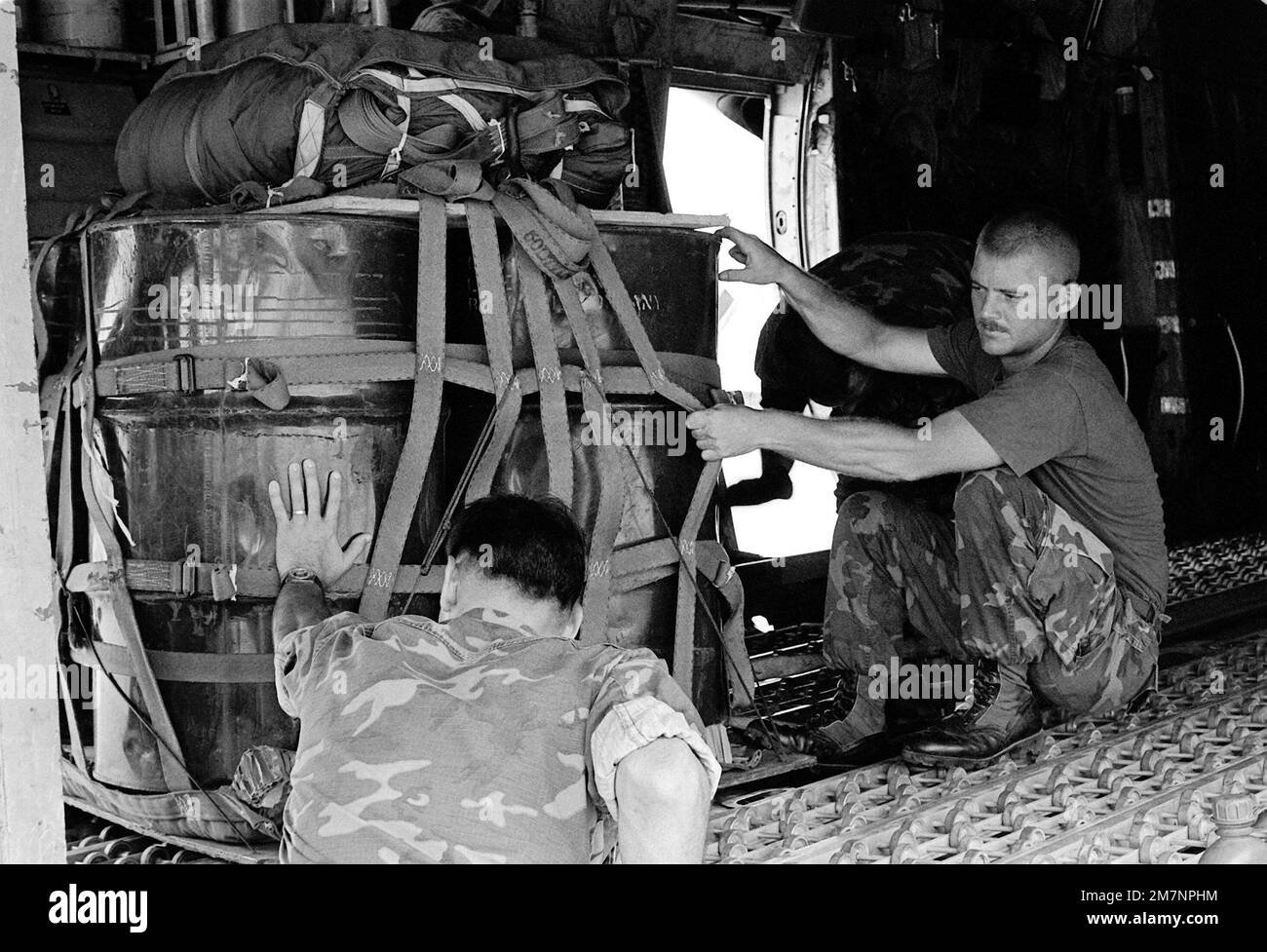 SGT Aguus R. Keydeniers gives SGT Robert C. Bunce a helping hand at loading a pallet of 50-gallon drums onto a C-130 Hercules aircraft. Base: Marine Corps Air Station, Futema State: Okinawa Country: Japan (JPN) Stock Photo