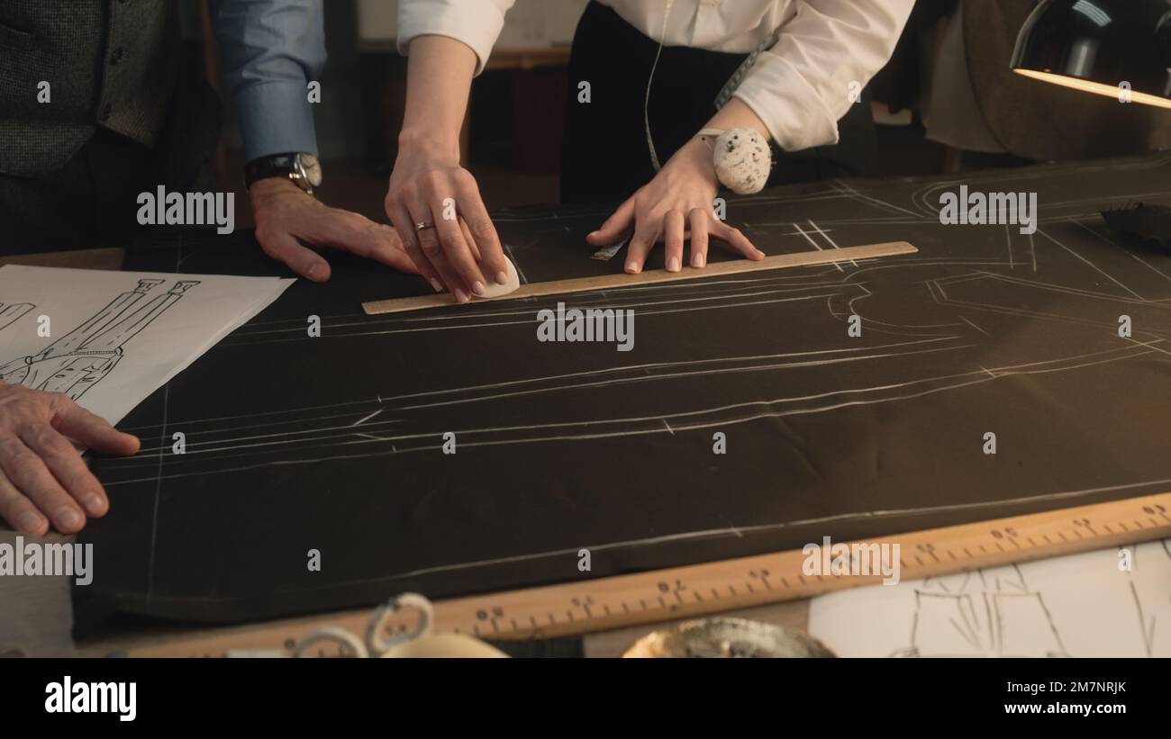 Male and female tailors transfer the sketch of future clothes to the ...