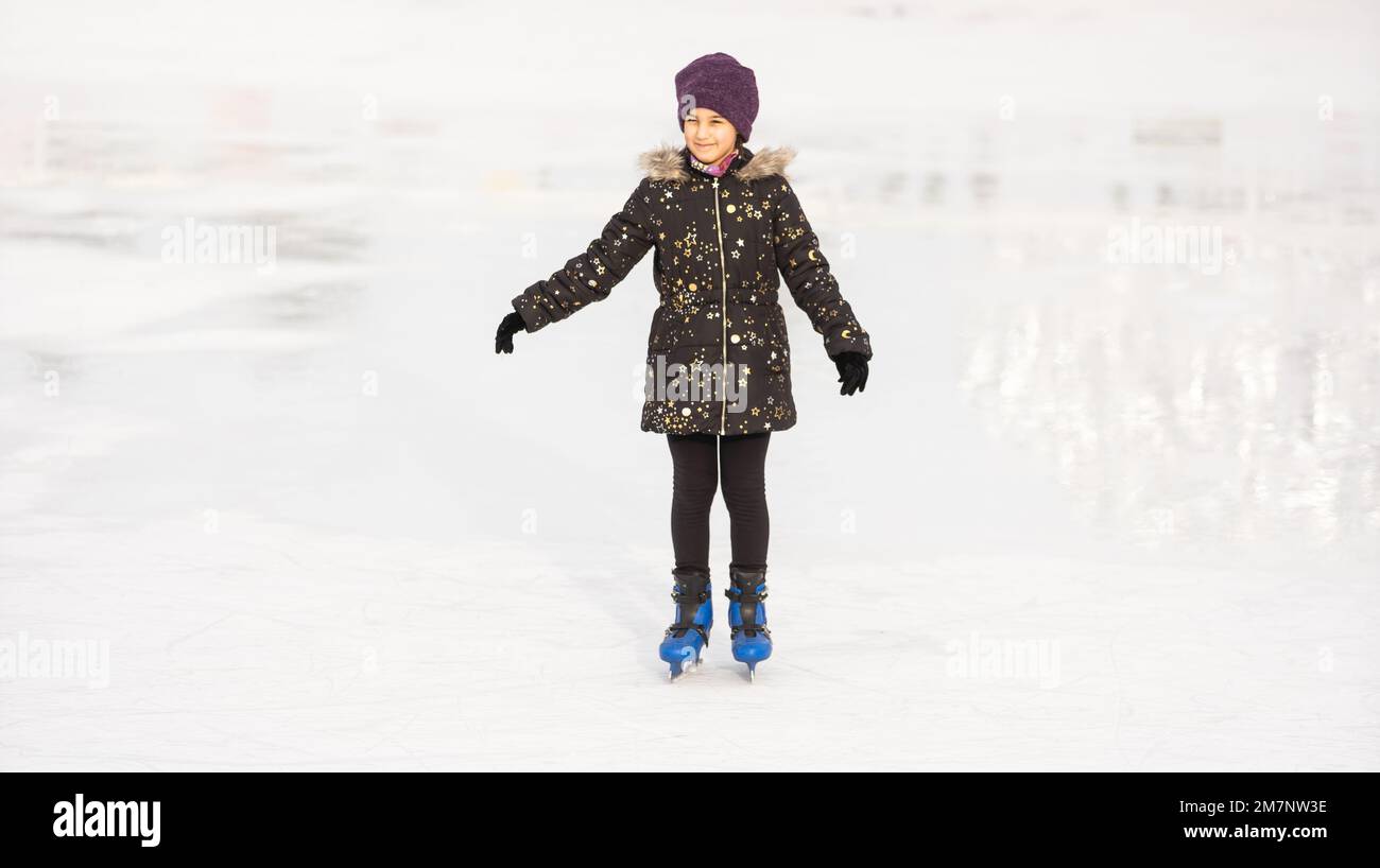 Adorable little girl in winter clothes skating on ice rink Stock Photo Alamy