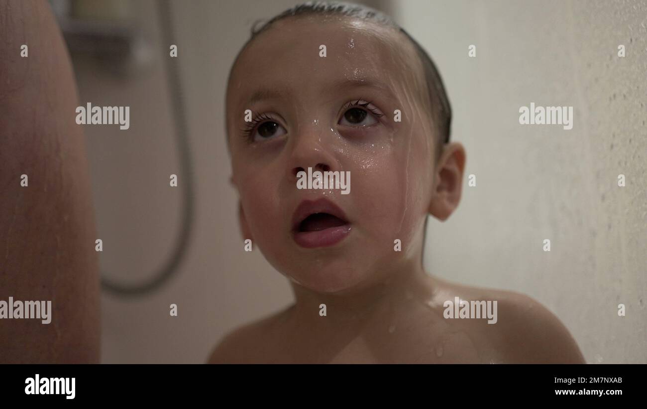 Baby toddler child rubbing face and eyes inside shower bath Stock Photo