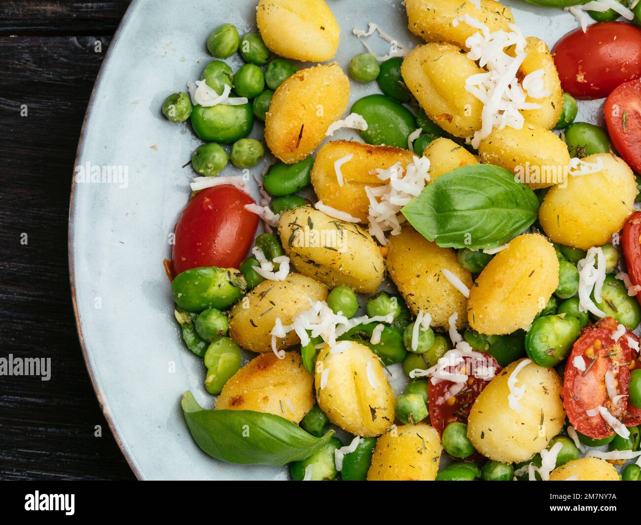 Fried gnocchi with fava beans, peas, cherry tomatoes and vegan cheese