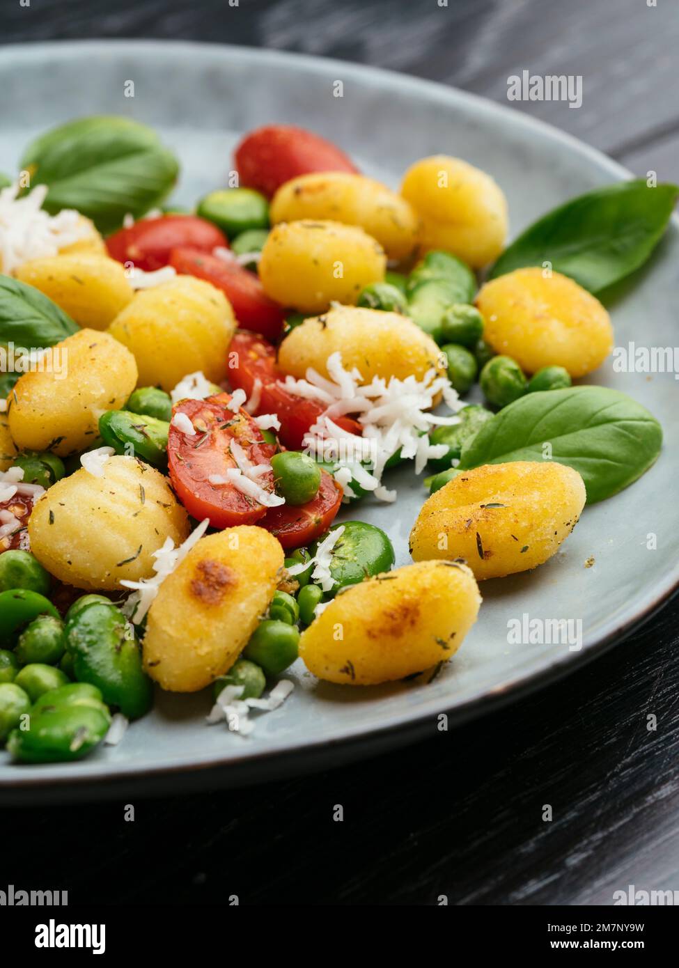 Fried gnocchi with fava beans, peas, cherry tomatoes and vegan cheese
