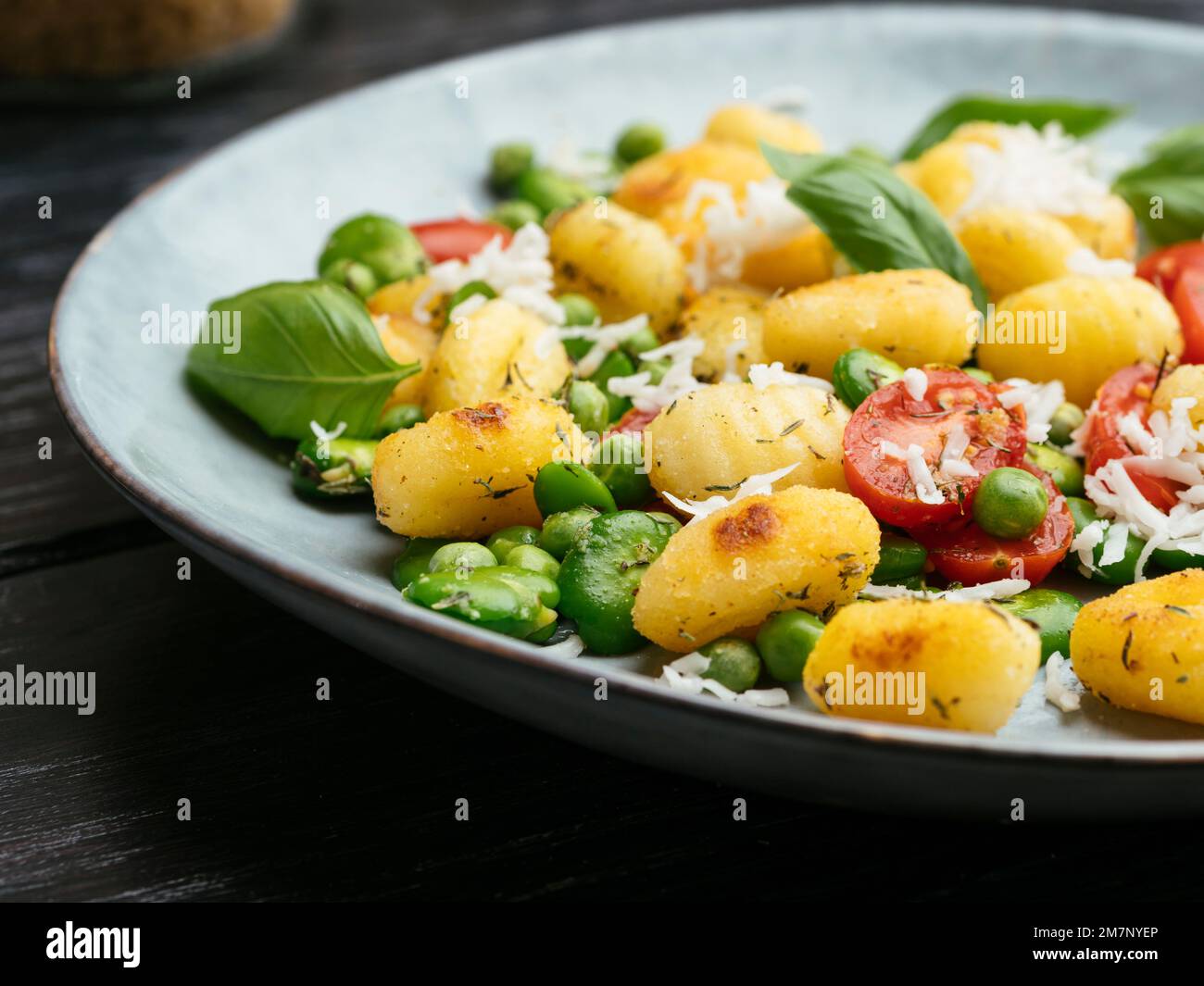 Fried gnocchi with fava beans, peas, cherry tomatoes and vegan cheese