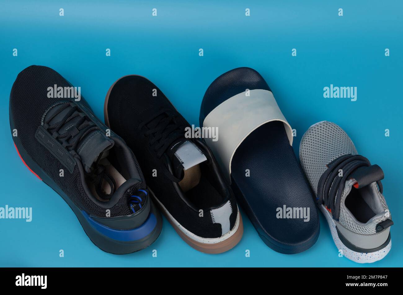 Line of different new shoes perspective view isolated on blue studio background Stock Photo