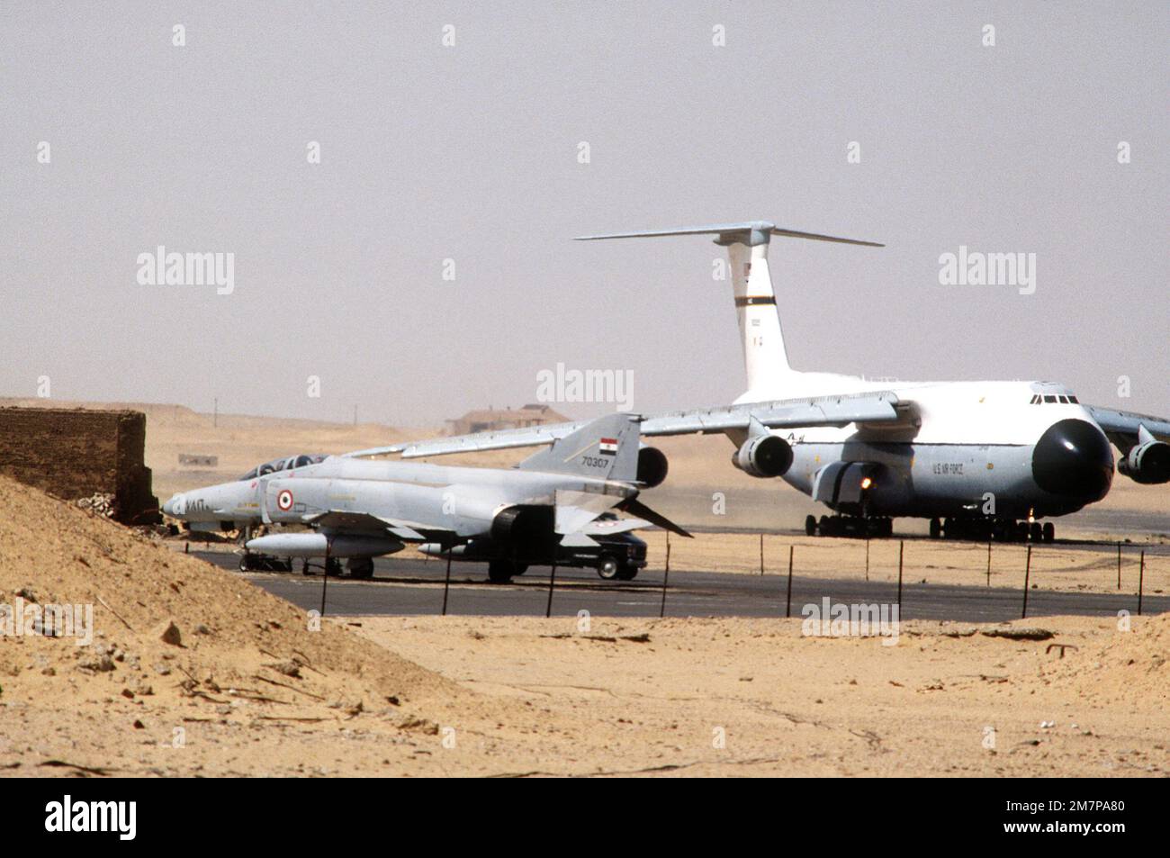 A right front view of a C-5A Galaxy aircraft taxiing with an Egyptian air force F-4E Phantom II aircraft in the foreground during exercise PROUD PHANTOM. Subject Operation/Series: PROUD PHANTOM Base: Cairo West Country: Egypt (EGY) Stock Photo