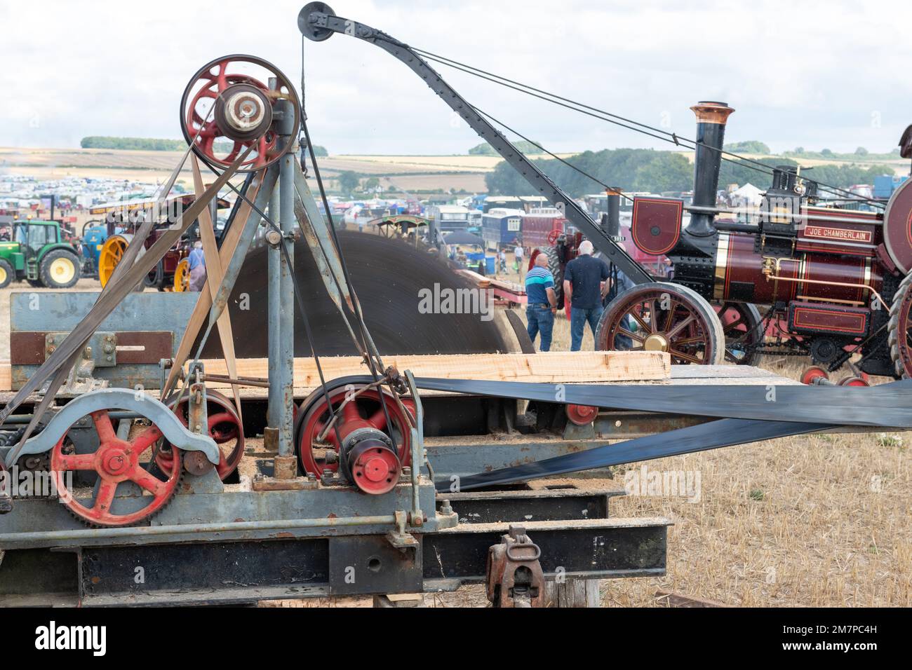 Tarrant Hinton.Dorset.United Kingdom.August 25th 2022.An old fashioned circular saw is being used to cut timber while a 1909 Burrell crane engine is w Stock Photo