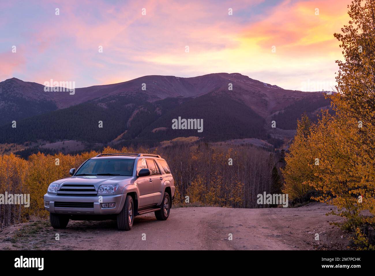 Exploring Autumn Sunset Valley - A SUV on a dirt backcountry road in a valley at base of Mount Elbert on a colorful Autumn evening. Twin Lakes, CO, US. Stock Photo