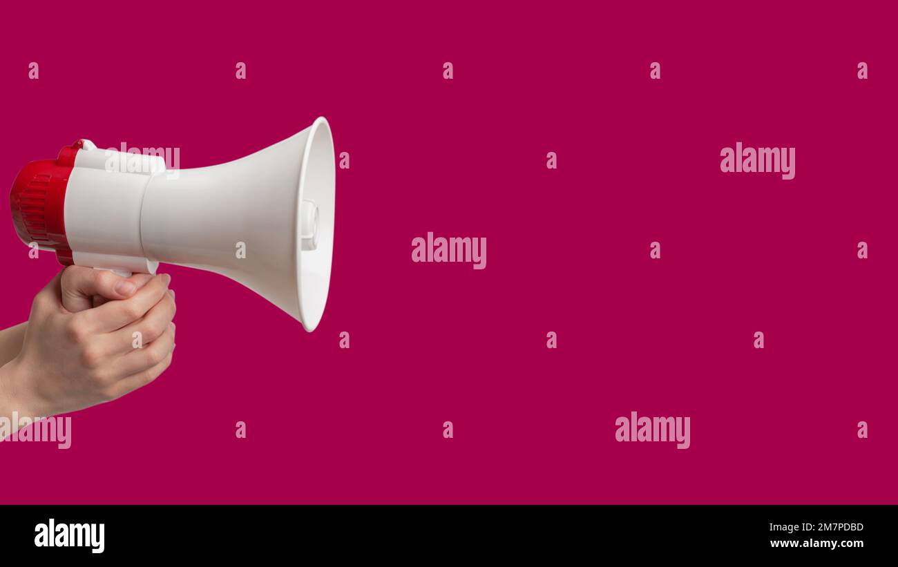 Megaphone in woman hands on a purple  background.  Copy space. Stock Photo