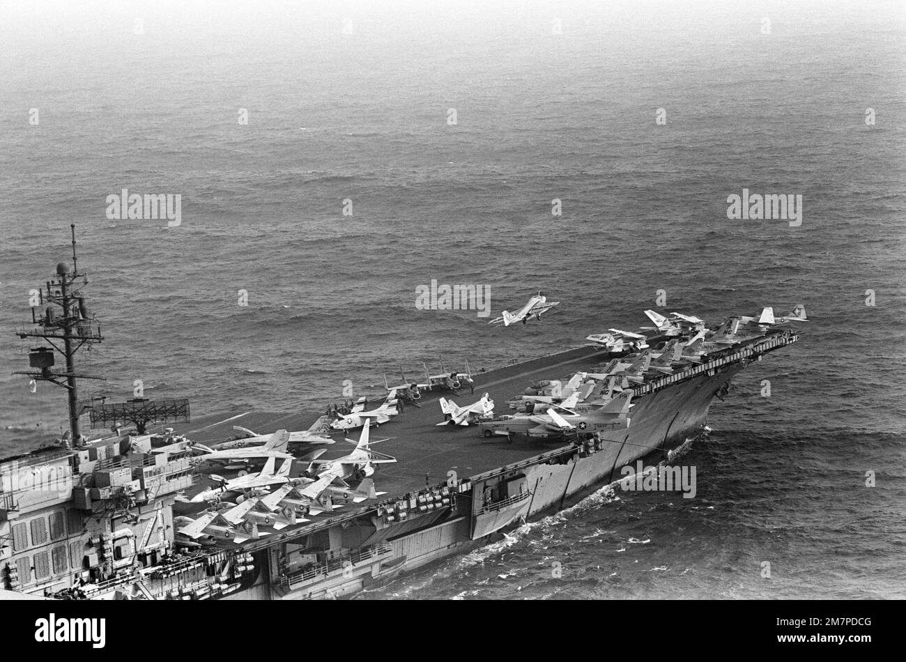 An aerial starboard view of the forward section of the Kitty Hawk class aircraft carrier USS CONSTELLATION (CV 64), as an A-6E Intruder aircraft begins to bank to the left after a catapult assisted takeoff from the flight deck. Country: Unknown Stock Photo