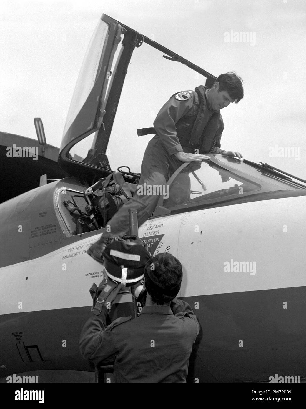 A Royal Air Force pilot helps a U.S. Air Force pilot climb into an