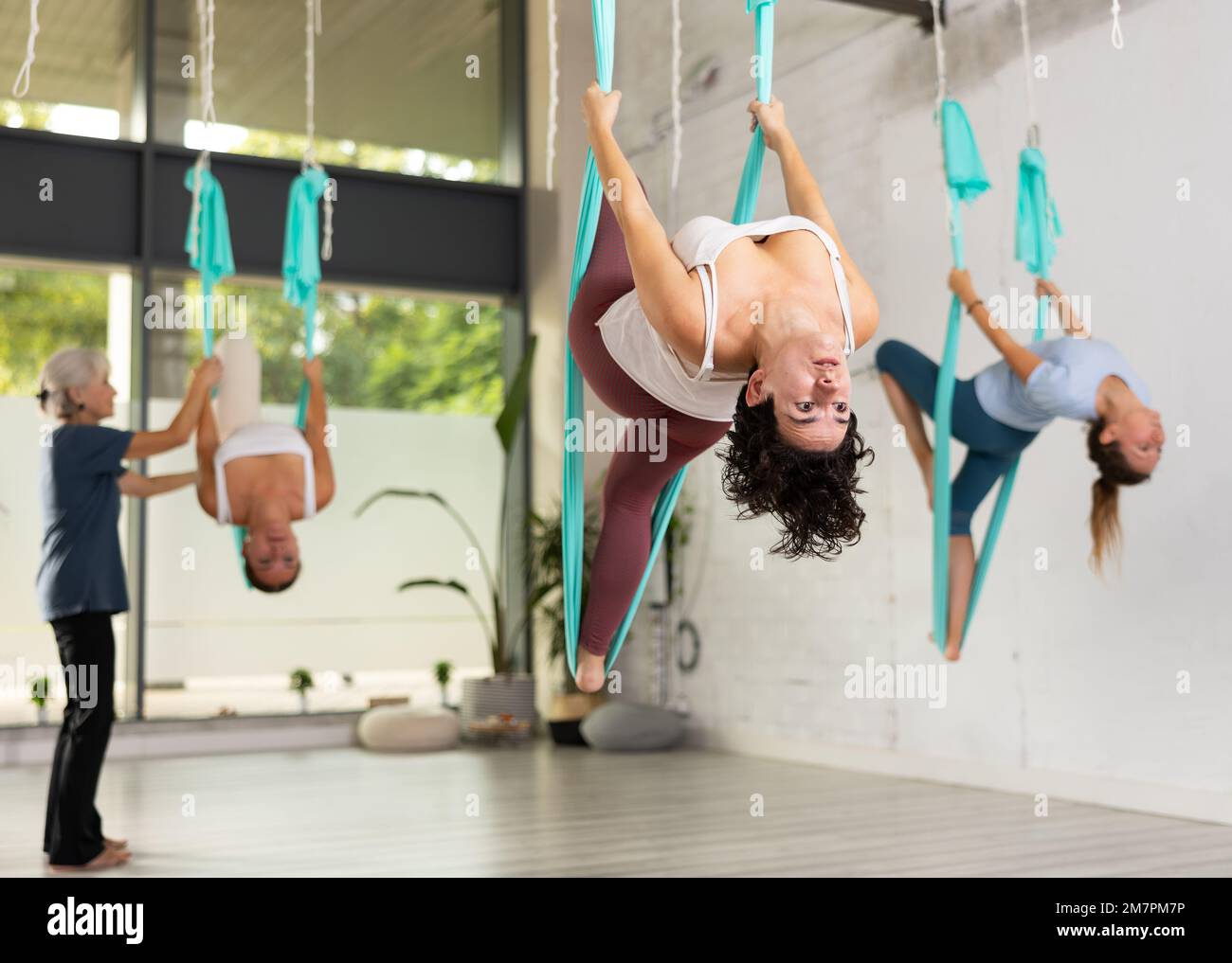 Athletic women hanging upside down in hammock. Fly yoga Stock Photo - Alamy