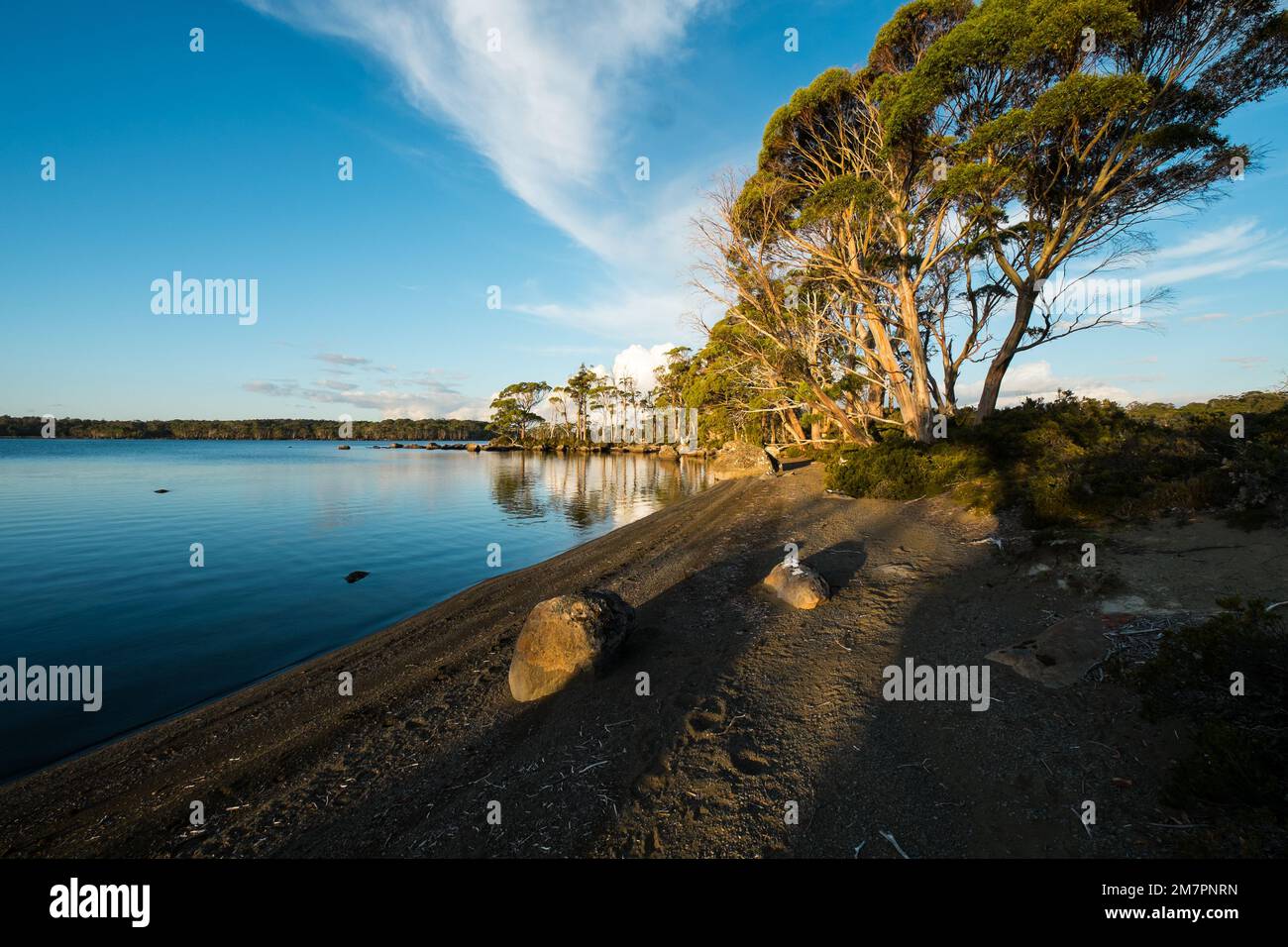 A setting sun over a boulder beach at Lake Ina Tasmania. Stock Photo