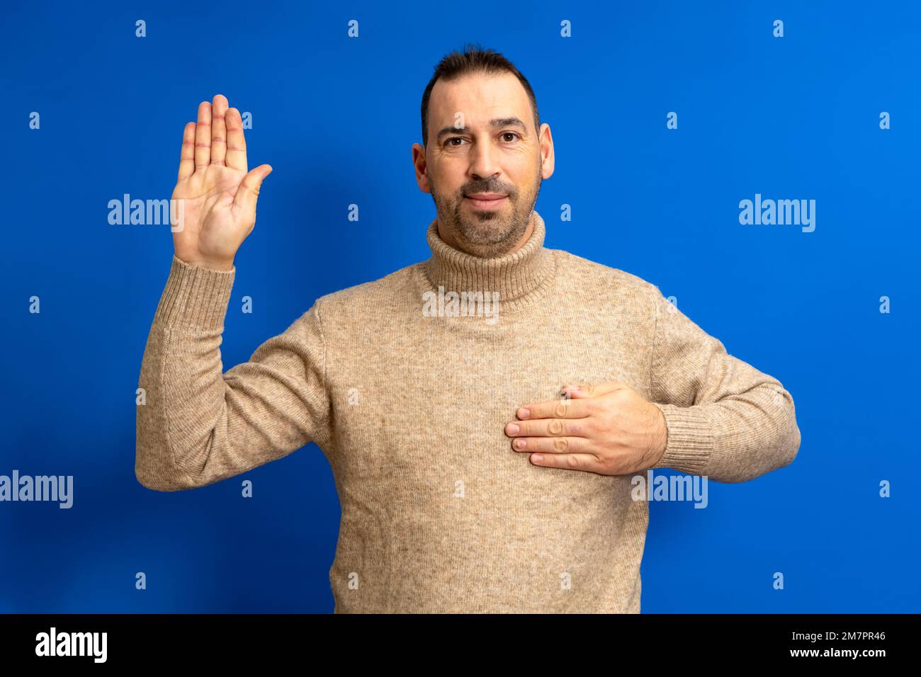Bearded hispanic man in turtleneck with hand on chest making an oath of honor, swears to tell the whole truth without fear of consequences. Isolated Stock Photo