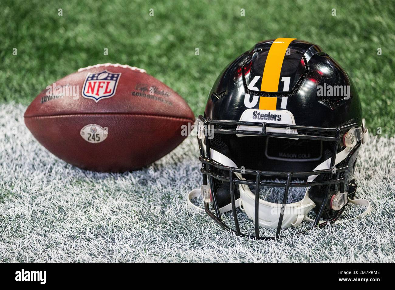 A Pittsburgh Steelers helmet sits on the field with a football