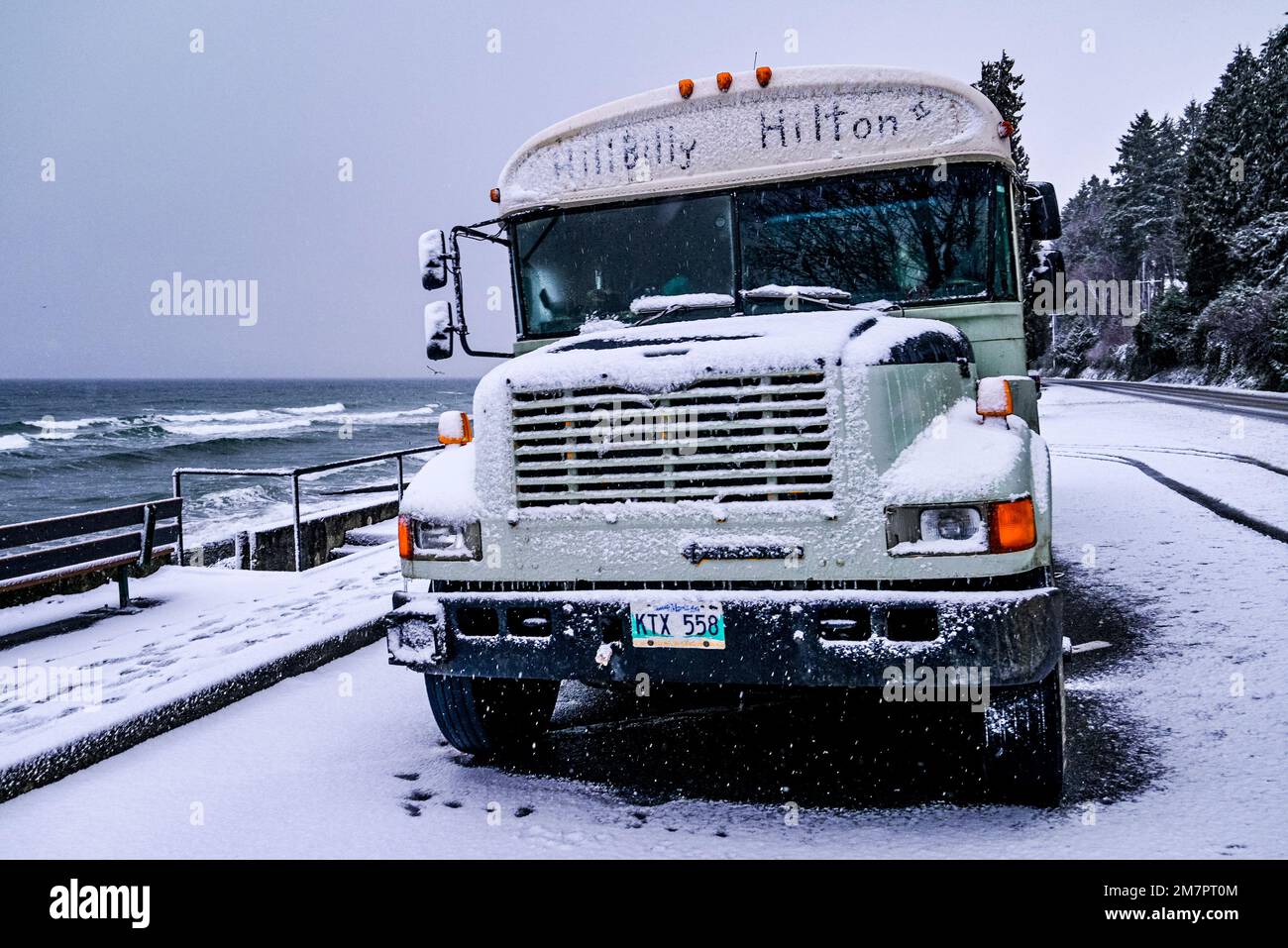 HillBilly Hilton, old school bus, parked at Qualicum Beach in snowstorm, Vancouver Island, British Columbia, Canada Stock Photo