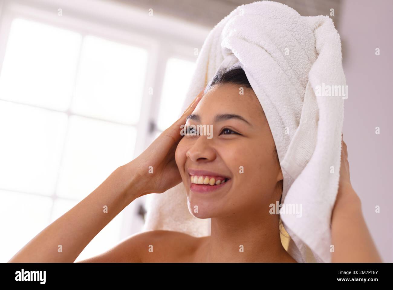 Happy biracial woman wearing towel on head smiling in bathroom, with copy space Stock Photo Alamy