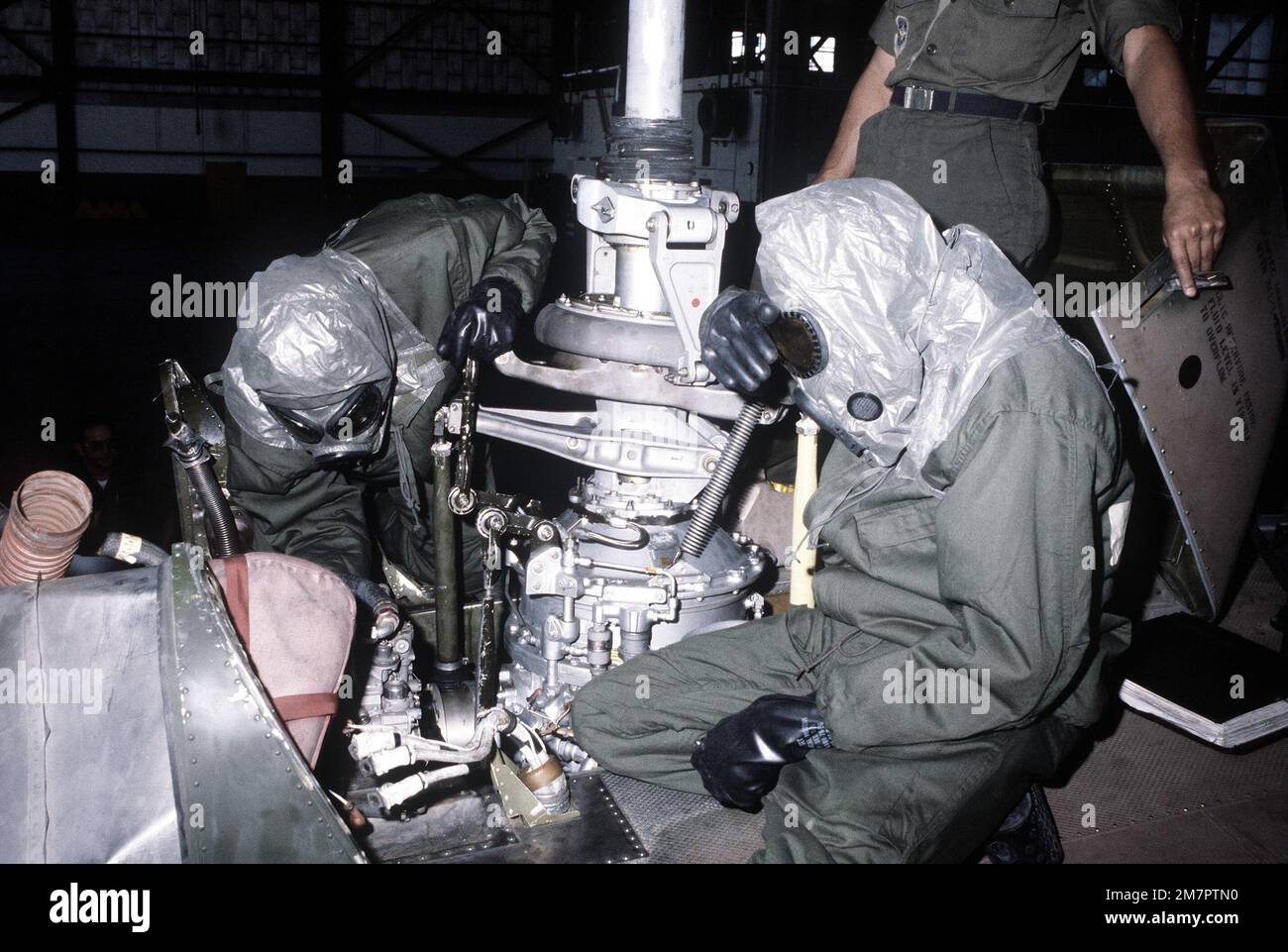 Maintenance crewmen in protective clothing work on the fuel control of