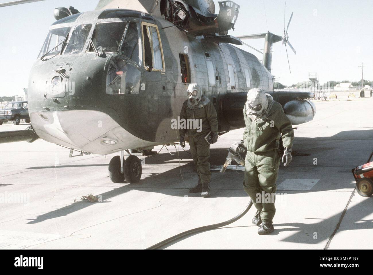 Ground crewmen in protective clothing complete refueling of an H-53 Sea Stallion helicopter during a chemical warfare training exercise. Base: Kirtland Air Force Base State: New Mexico (NM) Country: United States Of America (USA) Stock Photo