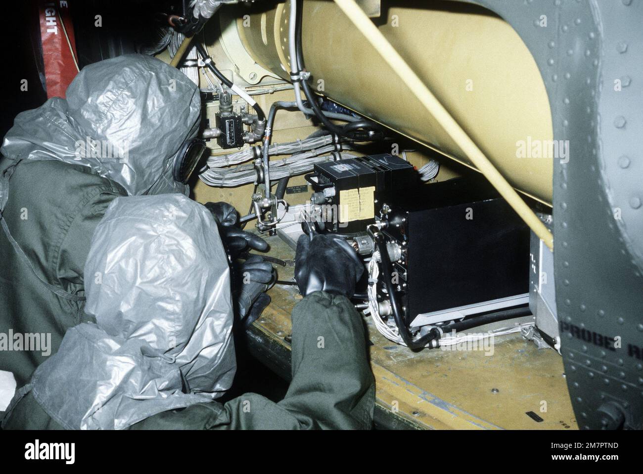 Ground crewmen in protective clothing perform engine maintenance on an H-53 Sea Stallion helicopter during a chemical warfare training exercise. Base: Kirtland Air Force Base State: New Mexico (NM) Country: United States Of America (USA) Stock Photo