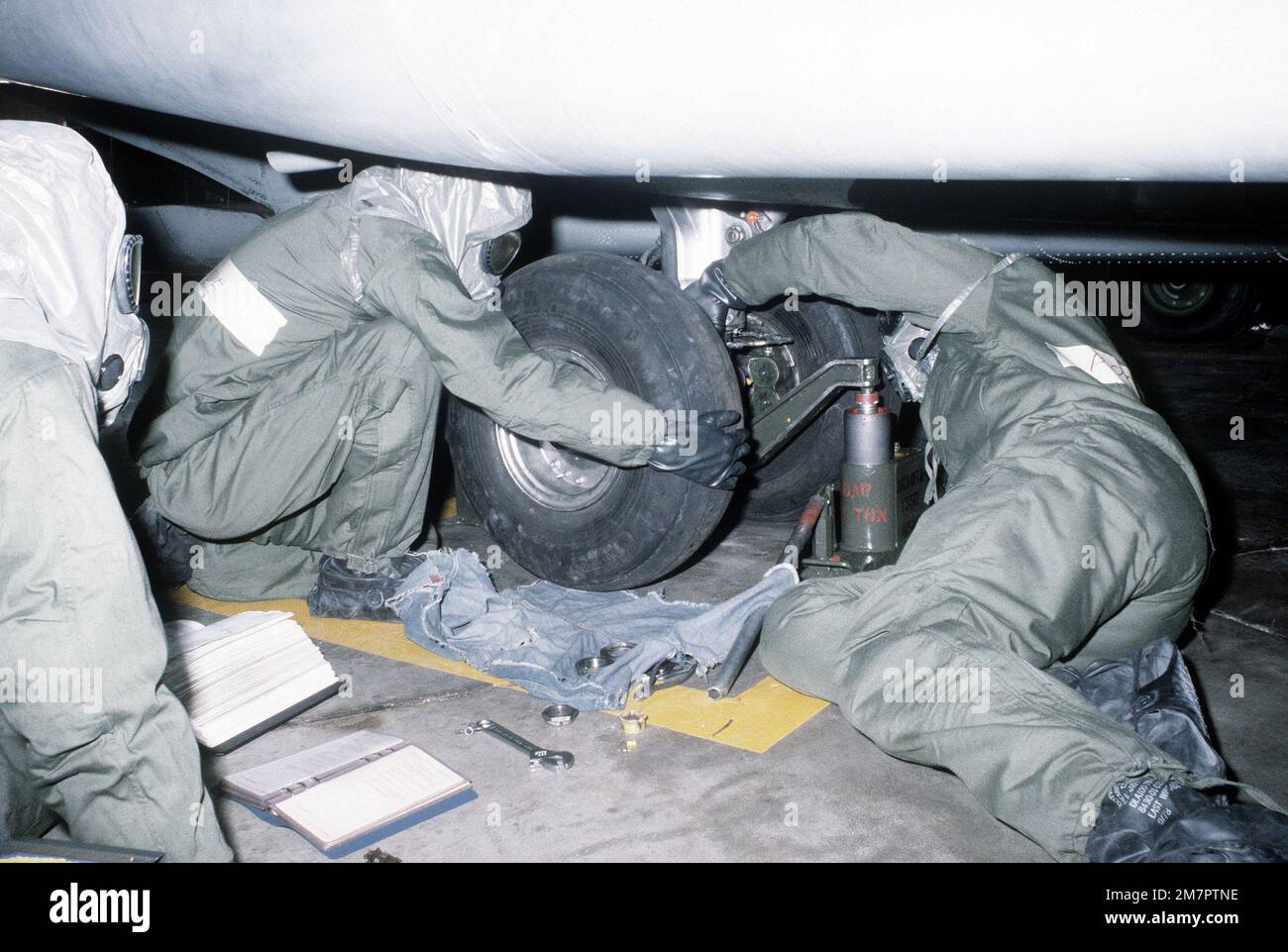Ground crewmen in protective clothing remove the tire from an H-53 Sea Stallion helicopter during a chemical warfare training exercise. Base: Kirtland Air Force Base State: New Mexico (NM) Country: United States Of America (USA) Stock Photo