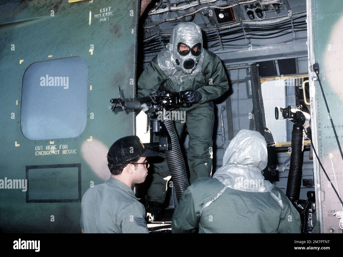 Three ground crewmen, two of whom are in protective clothing, load an H-53 Sea Stallion helicopter during a chemical warfare training exercise. Base: Kirtland Air Force Base State: New Mexico (NM) Country: United States Of America (USA) Stock Photo